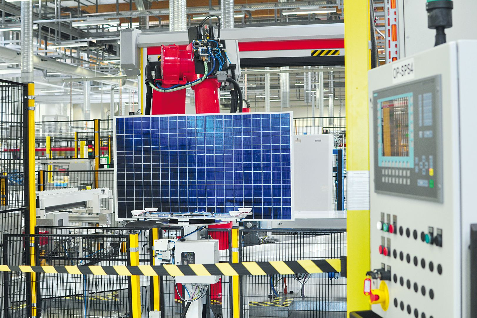 Industrieroboter montiert Solarmodul in Fabrik, Steuerpult und Sicherheitsabsperrung an Produktionslinie.