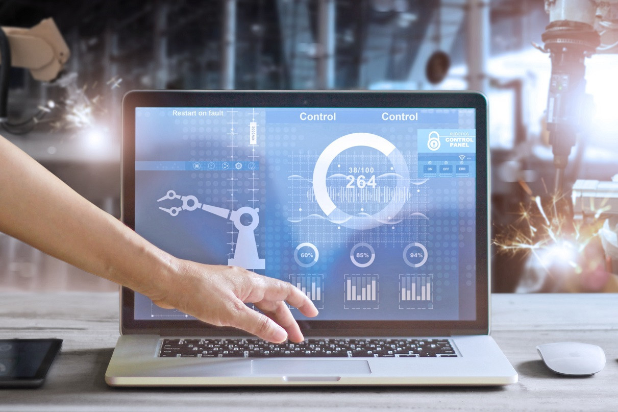 Hand interagiert mit industriellem Bedienfeld auf Laptop-Bildschirm.