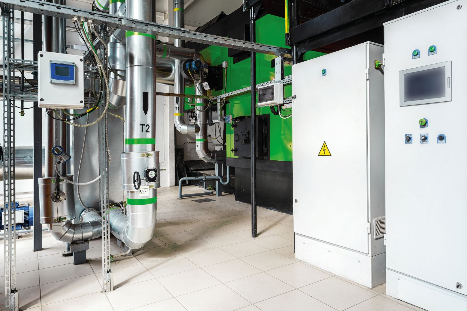 Technikraum mit Rohrleitungen, Messgeräten und Schaltschränken für industrielle Steuerung und Verteilung.
