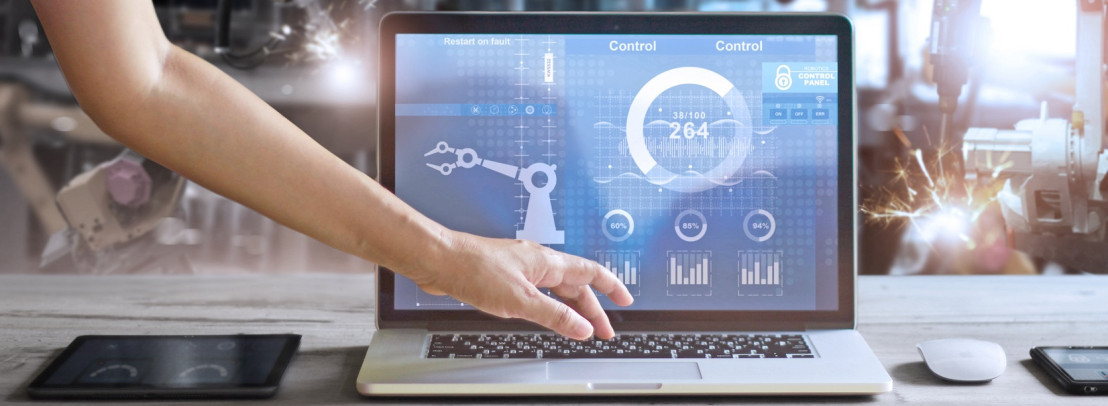 Webinarbild IT zu OT: Hand bedient Laptop mit Industrie-Dashboard in Fabrik.