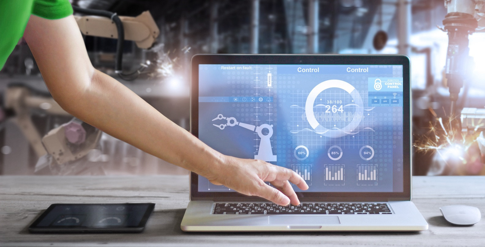 Hand bedient Laptop mit Robotik-Dashboard in Fabrikumgebung, Fokus auf Steuerungssicherheit und Datenanalyse